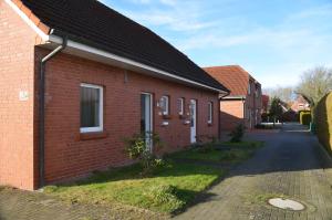 a red brick building with a street next to it at Haus Ute in Hooksiel +13 photos