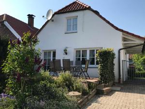 a white house with chairs in the garden at Fischerhaus in Hooksiel