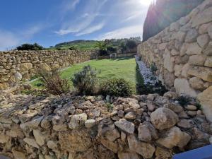 a stone wall next to a field and a river at Azure in Għarb