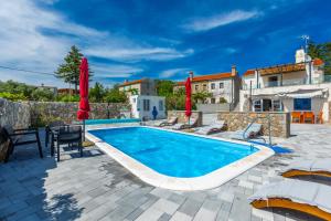 a pool with chairs and umbrellas next to a building at Villa 1900 in Kornić