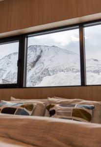 a bed in a room with a view of snow covered mountains at Beautiful lodge in Lofoten housing up to 6 guests! in Lyngværet