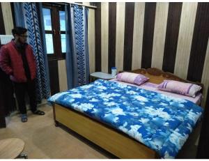 um homem ao lado de uma cama num quarto em Hotel Priya, Ghanghariya em Pāndukeshwar