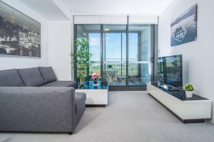 a living room with a couch and a television at Minimalism modern apartment*waterview*parking＊IGA in Sydney