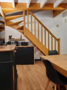 eine Küche und ein Esszimmer mit einem Holztisch und einer Treppe in der Unterkunft maison bonheur in Cerizay