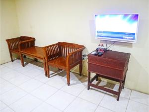 três cadeiras de madeira e uma televisão e um piano em D'Hans Hotel em Surabaya