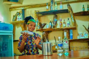 une femme se tient au comptoir dans un bar dans l'établissement NGORONGORO CORRIDOR LODGE Karatu, à Karatu