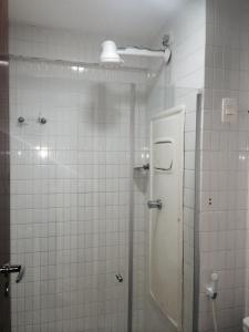 a white tiled bathroom with a shower and a toilet at Apartamento Tambaú in João Pessoa