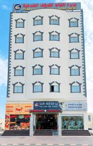a large white building with windows on the side of it at Pearl Hotel Apartment - اللؤلؤ للشقق الفندقية in Al Buraymī