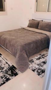 1 dormitorio con 1 cama con manta y alfombra en Sea View en ‘Akko