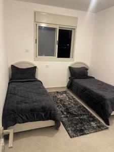 1 dormitorio con 2 camas y ventana en Sea View en ‘Akko