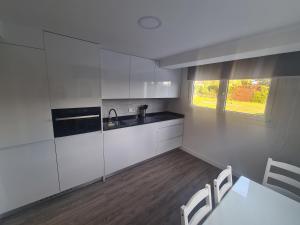 cocina con armarios blancos, mesa y sillas en Piso lujo 2 habitaciones (1), en Las Rozas de Madrid