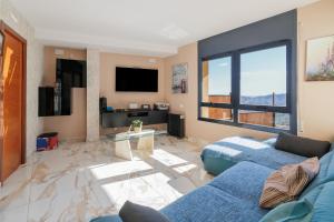 Can Camarasa في Cervelló: غرفة معيشة مع أريكة زرقاء ونافذة كبيرة