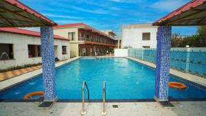 a swimming pool with blue tile columns in a building at Sea Queen Beach Resort On Beach in Mandarmoni