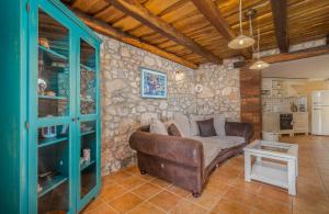 sala de estar con sofá y pared de piedra en Villa Pinia with pool, en Pinezici