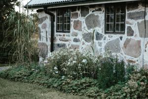 une maison en pierre avec des fleurs devant elle dans l'établissement Östra Nyrups Lantliv, à Höör