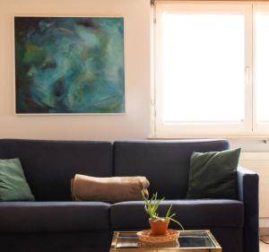 eine blaue Couch in einem Wohnzimmer mit einem Gemälde in der Unterkunft Casa Rosa in Arisdorf