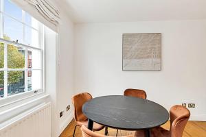 a dining room with a black table and chairs at One-Bedroom Abode With A Balcony In Central London in London