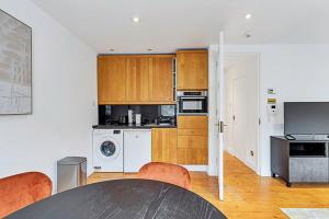 a kitchen with wooden cabinets and a table with chairs at One-Bedroom Abode With A Balcony In Central London in London