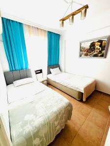 two beds in a room with blue curtains at Уютная квартира рядом с морем in Kemer