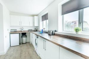 une cuisine avec des placards blancs et une grande fenêtre dans l'établissement Bliss: Spacious Beach Home, à Dymchurch
