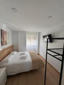 a white bedroom with a bed and a desk at Alojamientos Robustiana in Santander