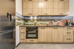 a kitchen with wooden cabinets and a mural on the wall at RentPlanet - Apartament Wyszyńskiego 56 in Wrocław