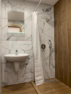 uma casa de banho branca com um lavatório e um chuveiro em Borovets gardens Studios A11&A12 em Borovets