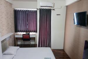 a room with a bed and a window with a desk at RedLiving Apartemen Riverview Residence - KiA 168 Tower Mahakam in Tegalgede