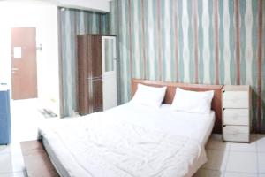 a bedroom with a large white bed and a striped wall at RedLiving Apartemen Riverview Residence - KiA 168 Tower Mahakam in Tegalgede