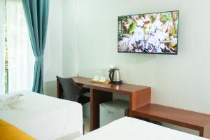Habitación de hotel con escritorio y TV en la pared en Bloom Boracay en Boracay