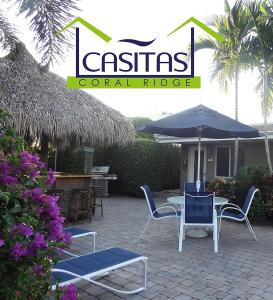 een patio met een tafel en stoelen en een parasol bij Casitas Coral Ridge in Fort Lauderdale