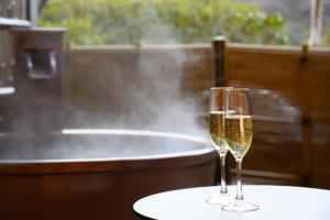 two glasses of champagne sitting on a table in front of a bath tub at Fukuichi in Shibukawa