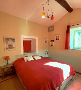 - une chambre avec un grand lit et une couverture rouge dans l'établissement Mas Suéjol, à Anduze