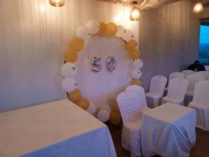 ALLY NGALI MOTEL في كيغالي: غرفة بطاولات بيضاء وكراسي بيضاء وبالونات