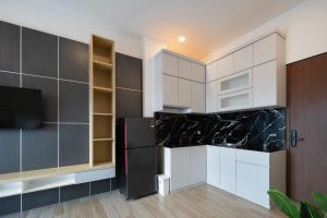 a kitchen with white cabinets and a black refrigerator at Cove Casagio in Jakarta