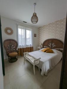 ein Schlafzimmer mit einem großen Bett und einem Stuhl in der Unterkunft Le Clos des Gazanias in Grignols