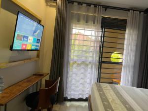 a room with a bed and a television and a window at Ashleys Hotel in Kampala