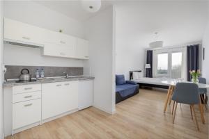 eine Küche und ein Wohnzimmer mit weißen Schränken und einem Tisch in der Unterkunft Potulicka Comfort Studio in Stettin
