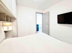 1 dormitorio blanco con 1 cama grande y TV en Best in Villasimius: modern, perfectly located, en Villasimius