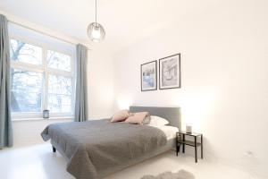 a white bedroom with a bed and a window at Glow Apartments, Apartamenty Śródmieście in Gdańsk