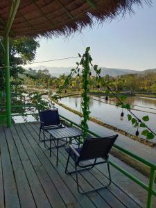 dwa krzesła i stół na tarasie obok rzeki w obiekcie Glamping Laos w mieście Luang Prabang
