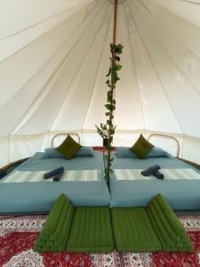 a bed in a canvas tent with green pillows at Glamping Laos in Luang Prabang