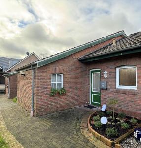 a brick house with a green door at Ferienhaus Tamko 95161 in Rhauderfehn