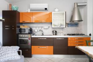 eine Küche mit orangefarbenen Schränken und einem Waschbecken in der Unterkunft Cara House Vista Mare in Àrbatax