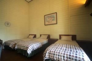 two beds sitting in a room with at Hotel Villa Rawa Pening Pratama by Aparian in Bandungan