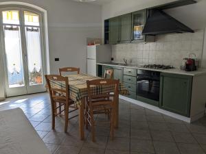 una cocina con armarios verdes, mesa y sillas en New Casa Arcobaleno apartments-Room holiday home, en Diano dʼAlba