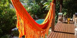 an orange hammock hanging from a porch with a pool at Quarto na Praia de Taquaras in Balneário Camboriú
