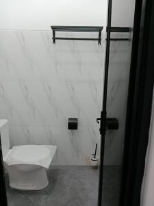 e bagno con servizi igienici e porta doccia in vetro. di De'kost & homestay tegal a Lebaksiu