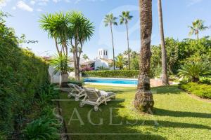 a villa with a swimming pool and palm trees at Jardines de las Golondrinas in Marbella