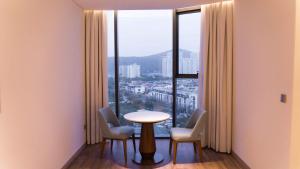 Habitación con mesa, sillas y ventana grande. en View Natural Wonders A La Carte Ha Long Bay VIE, en Ha Long